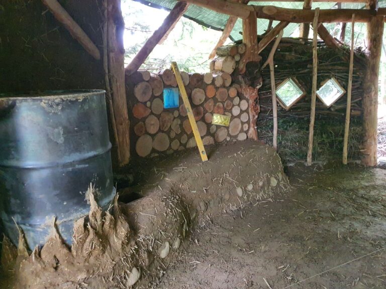 Rocket Mass Heater mit langer Ofenbank und Cordwood Wand