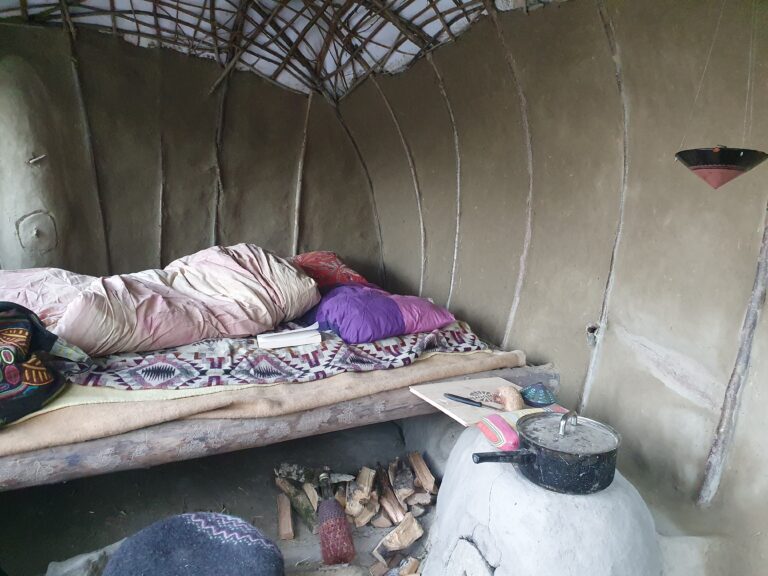 Der Küchenofen und das Bett in einem kleinen Naturbau Daheim