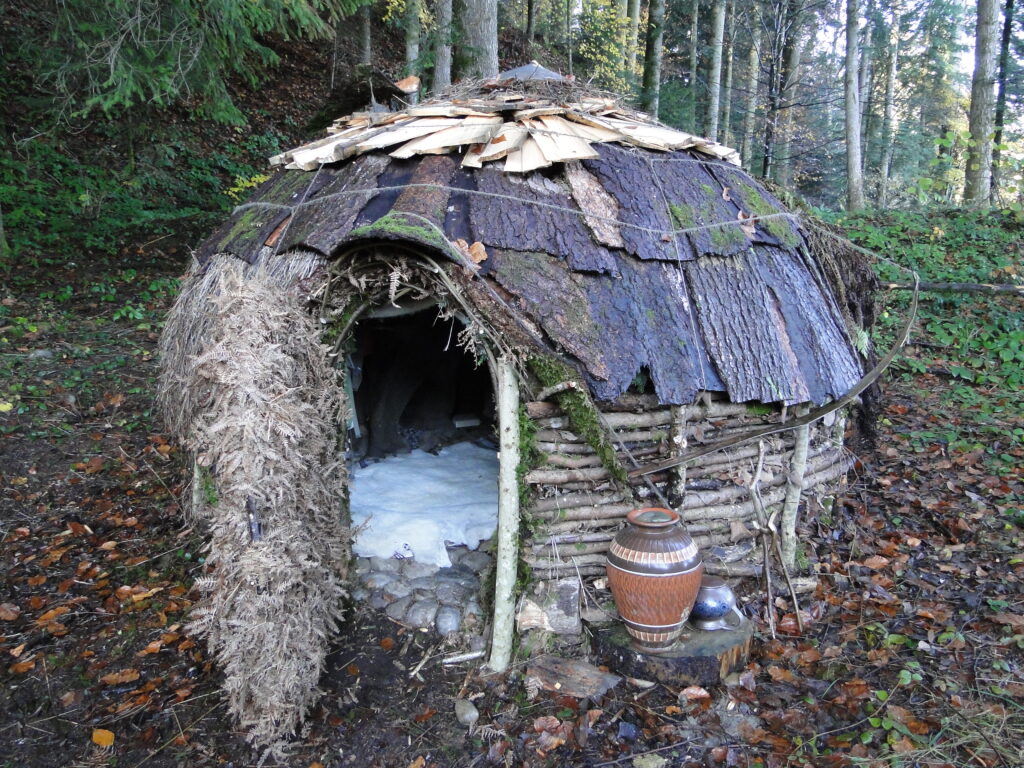 Eine runde, mit Holzschindlen und Rinde gedeckte Waldhütte