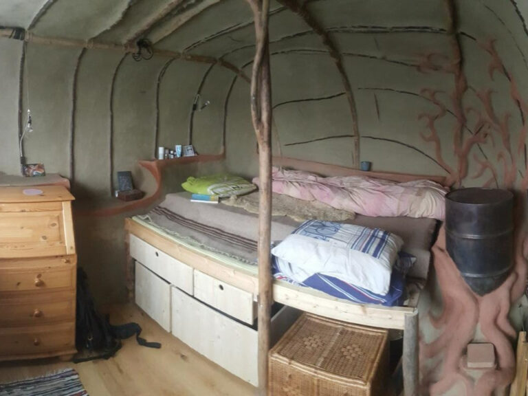 Ofen, Bett und Stauraum darunter in einem kleinen Erdhaus